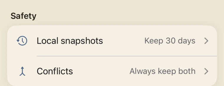 The Safety section of settings: a row reading 'Local snapshots - Keep 30 days' and a row reading 'Conflicts - Always keep both'.